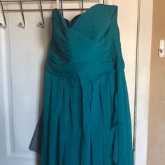 a teal dress hanging on a door with a hanger in front of it