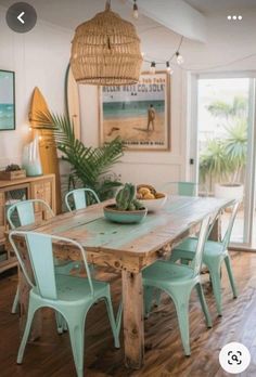 a dining room table with blue chairs and a bowl of fruit on top of it