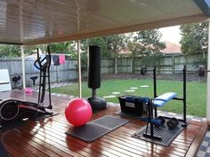 an outdoor gym area with exercise equipment and yoga balls on the floor in front of it