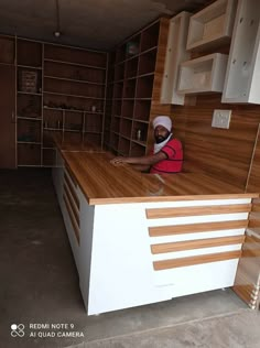 a man sitting on top of a counter in a kitchen next to cabinets and shelves