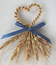 an ornament made out of wheat stalks with a heart shaped decoration on it