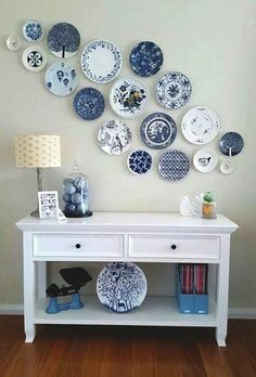 a white table topped with lots of blue and white plates on it's wall