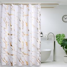 a shower curtain with gold paint on it next to a white sink and potted plant