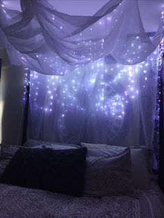 a bed with lights hanging from it's ceiling and curtains over the headboard