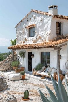 a white house sitting on top of a lush green hillside next to a cactus plant