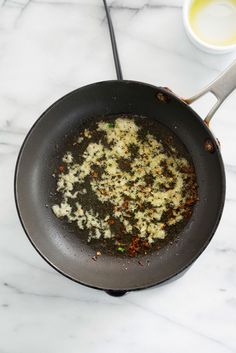 a frying pan filled with food sitting on top of a white marble countertop