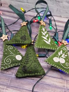 four green christmas tree ornaments with lights on the top and one is hanging from a string