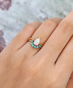 a woman's hand with a diamond and turquoise stone ring on her left hand