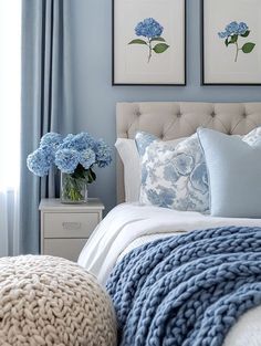 a bedroom with blue walls and white bedding, two framed pictures on the wall