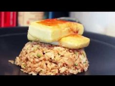 two pieces of food are stacked on top of each other in a black plate with rice and banana slices