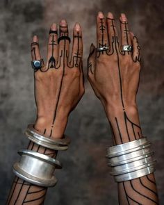 two hands with rings and tattoos on them