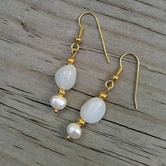 "Two classic jewels in brilliant white: milky white Peruvian opals are paired with white freshwater pearls in a stunningly classic look 💕  These are the perfect jewelry gift for someone with a birthday in June (birthstone= pearl!) or October (birthstone= opal!). 💕 Peruvian opals 💕 Freshwater pearls 💕 22K gold-plated wires & accents This pair of opals are milky white and faintly translucent.  Their faint bluish-white shade is more noticable against the creamy white of the pearls. Did you know Dainty White Moonstone Jewelry, White Elegant Pearl Earrings, Elegant White Gemstone Pearl Earrings, Delicate White Jewelry With Matching Earrings, Elegant Pearl Drop Moonstone Jewelry, Elegant Moonstone Pearl Drop Jewelry, Elegant Moonstone Jewelry With Pearl Drop, Elegant Pearl Birthstone Earrings As Gift, Elegant Pearl Birthstone Earrings For Gift