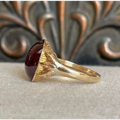 Step back to a time of refined elegance with this Victorian Garnet Signet Ring, a splendid piece that exudes the charm of the early 19th century. This impressive ring features a large cabochon garnet, measuring 14.4x11.5 mm, set in a distinctive signet style. The garnet is closed backed, emphasizing its rich, deep color and classic appeal.  Originally crafted around 1840-50, the ring has been expertly re-shanked; while the top mounting and the intricately detailed clawed feet are made of 15 karat gold, the band itself has been updated with 9 karat gold. Measuring 15.3 mm north to south and 19.3 mm across at the face, the ring sits 6 mm off the finger and narrows to 2.5 mm at the back. Weighing 4.8 grams and sized at 10, this well-loved ring showcases both historical craftsmanship and a tim Timeless Cabochon Rings For Formal Occasions, Formal Cabochon Ruby Ring, Timeless Gold Dome Ring With Cabochon, Classic Garnet Rings With Bezel Setting, Elegant Domed Cabochons For Gifts, Timeless Yellow Gold Dome Ring With Cabochon, Classic Yellow Gold Signet Ring With Cabochon, Heirloom Red Ruby Cabochon Ring, Heirloom Red Cabochon Ruby Ring