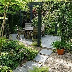 an outdoor patio with table and chairs surrounded by greenery