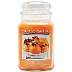 an orange candle is sitting on a white surface with the words village candle in front of it