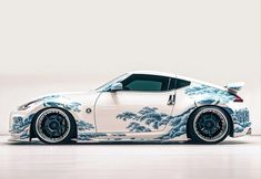 a white sports car with blue and white designs on it's hood, parked in a studio