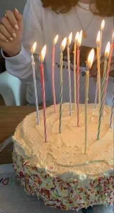 a woman sitting in front of a cake with lit candles