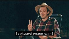 a man sitting in a chair with the words awkward peace sign written on his hand