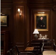 a room with wooden paneling and paintings on the wall, along with two chairs