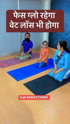 three people are sitting on yoga mats in the middle of a room with blue walls