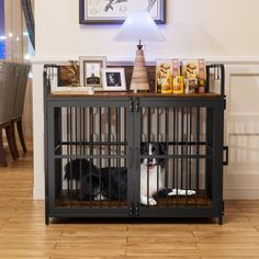 a black and white dog sitting in a cage next to a table with pictures on it