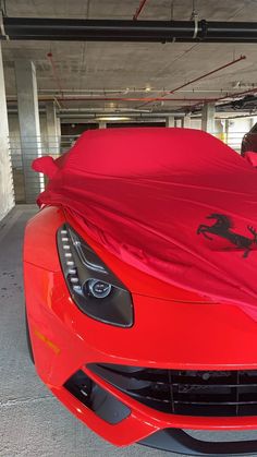 a red sports car covered in a tarp with a ferrari logo on the hood