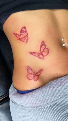 two pink butterflies on the side of a woman's stomach, both with small tattoos