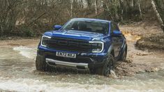 a blue truck is driving through some water