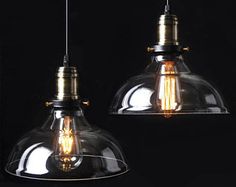 two clear glass pendant lights hanging from a black ceiling with one light turned on and the other turned off