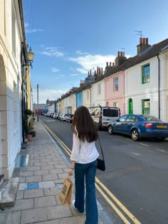 a woman is walking down the sidewalk with her shopping bags in hand and cars parked on the side of the street