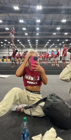 a woman taking a selfie while sitting on the floor in front of other people