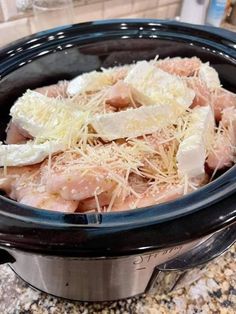 a crock pot filled with meat and cheese on top of a granite countertop