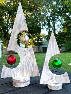 two christmas ornaments sitting on top of a wooden table in the middle of a yard