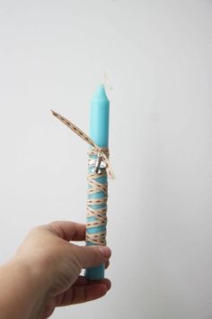 a person holding a small blue candle wrapped in twine