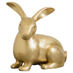 a golden rabbit statue sitting on top of a white surface