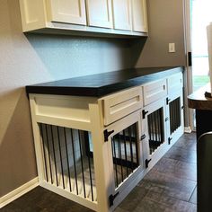 a dog kennel in the corner of a room with white cabinets and black counter tops