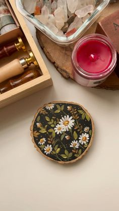 a wooden box filled with lots of different items next to a candle and some rocks