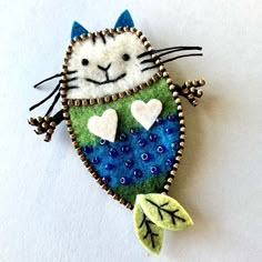 a felt cat ornament with leaves and hearts