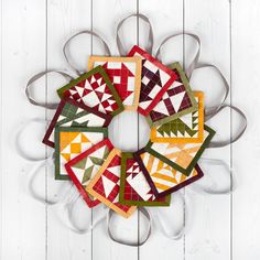 a wreath made out of quilts and ribbon on top of a white wooden wall