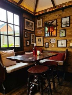 a table with two stools in front of it and pictures on the wall behind it