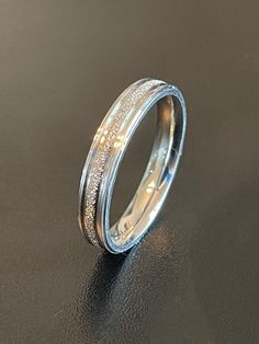 a wedding band with white gold and diamonds on the inside, sitting on a black surface