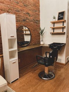 a salon chair in front of a brick wall with shelves on either side and a mirror above it