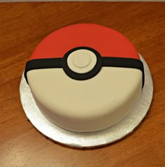 a pokemon cake on a wooden table with white frosting and red and black decorations