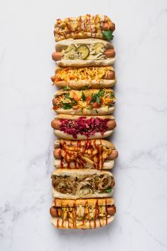 five hot dogs lined up on top of each other with toppings and condiments