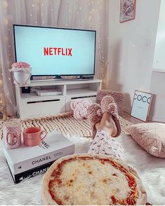 a person laying on a bed with a pizza in front of a tv and some pillows