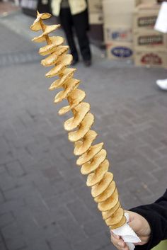 a person is holding up a long skewer with food on it's side