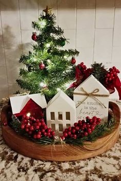 a small christmas tree in a wooden bowl with houses on it and decorations around the base