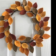 a wreath made out of felt leaves on the front door's white wooden door