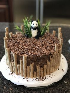 a cake decorated with bamboo sticks and a panda figurine sitting on top of it