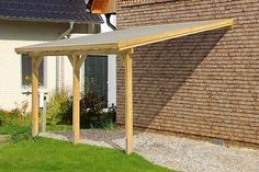 a wooden pergola in front of a brick building with green grass and flowers